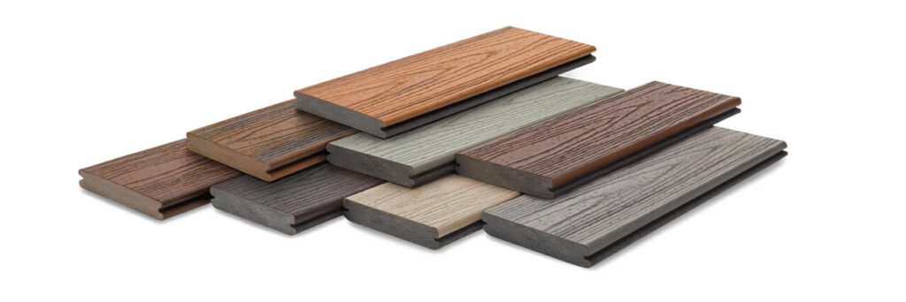 A variety of composite decking boards arranged to show different colors and wood-grain textures. These boards demonstrate factory-finished surfaces that eliminate the need for painting and staining.