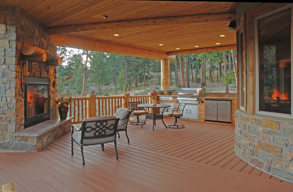Covered outdoor living space finished with Envision EverGrain Redwood composite decking. The rich, earthy tone of the boards complements stone accents, wood beams, and a built-in fireplace. The deep-grain texture enhances the natural wood appearance while supporting a low-maintenance deck surface.