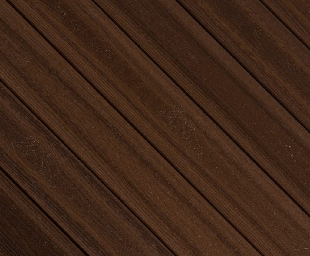 Close-up swatch of Envision Ridge Premium Black Walnut composite decking showcasing deep brown tones with darker grain accents inspired by traditional walnut wood.