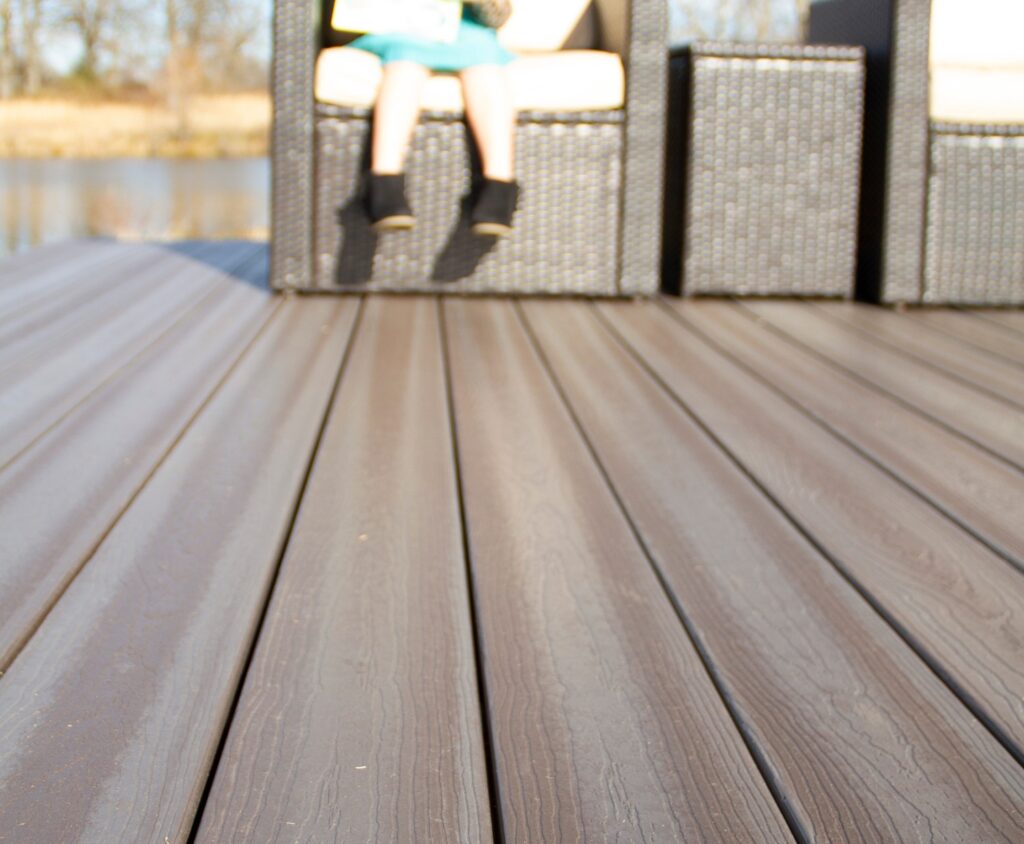 Close-up view of Envision Ridge Premium Gunstock decking boards showing realistic wood grain texture and consistent color variation on a lakeside deck.