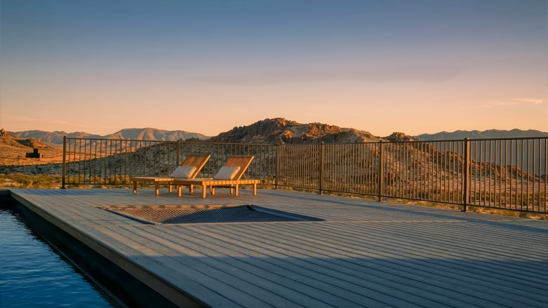 Trex Refuge decking in Point Reyes color with modern black railing, sun loungers, and panoramic desert mountain views at sunset.