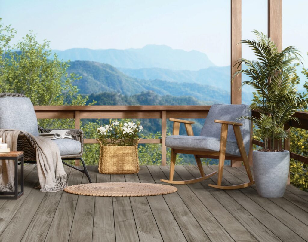 Fiberon Novus Weathered Ipe composite decking installed on a scenic mountain-view deck with modern outdoor seating. The muted gray-brown boards complement natural wood railings and create a calm, contemporary outdoor living space.