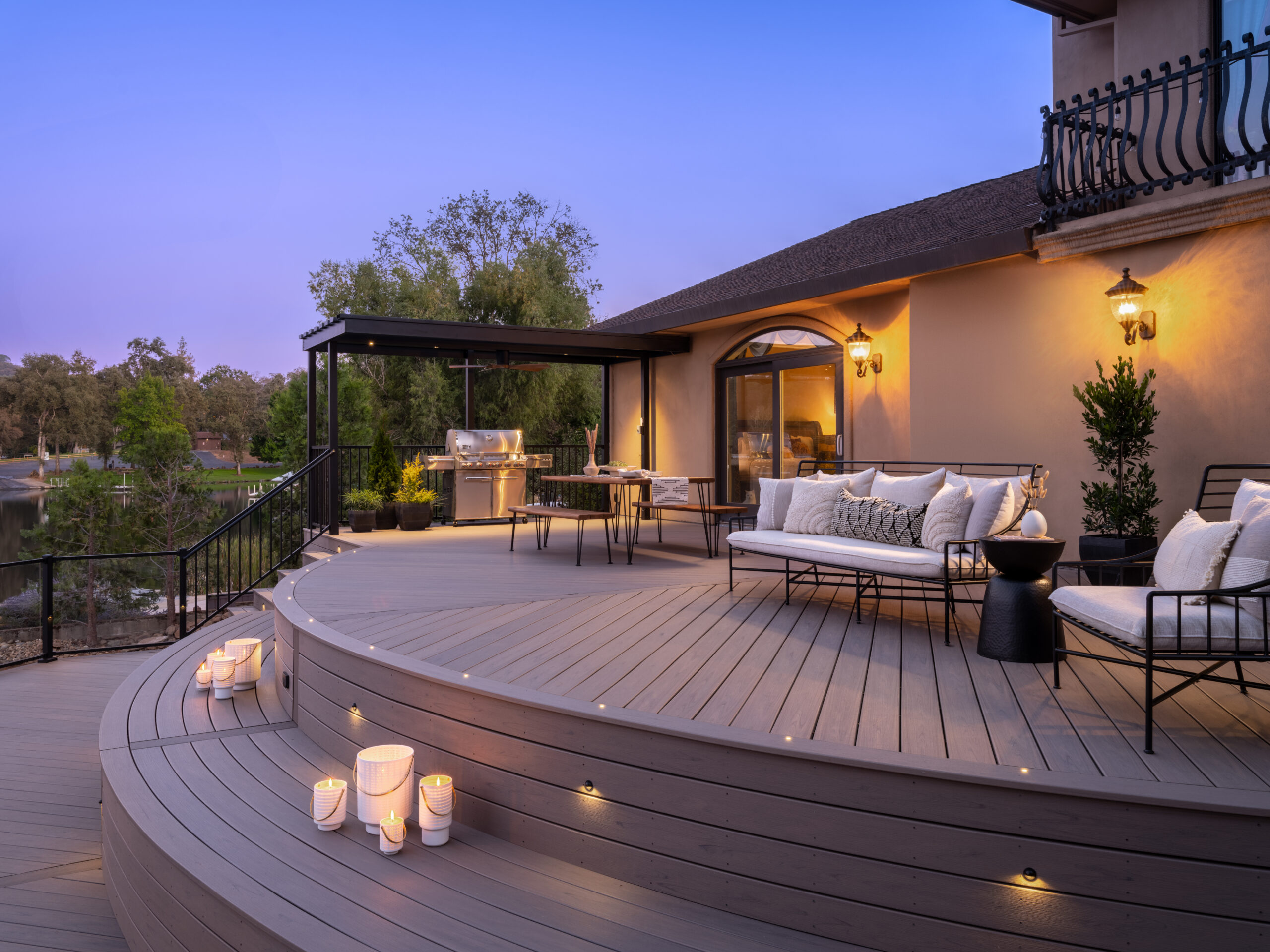 Modern composite deck installed with Trex hidden fasteners featuring a smooth, seamless surface without visible screws. The curved deck design includes integrated lighting, metal railing, and outdoor seating, highlighting the clean finish achieved with hidden deck fasteners.