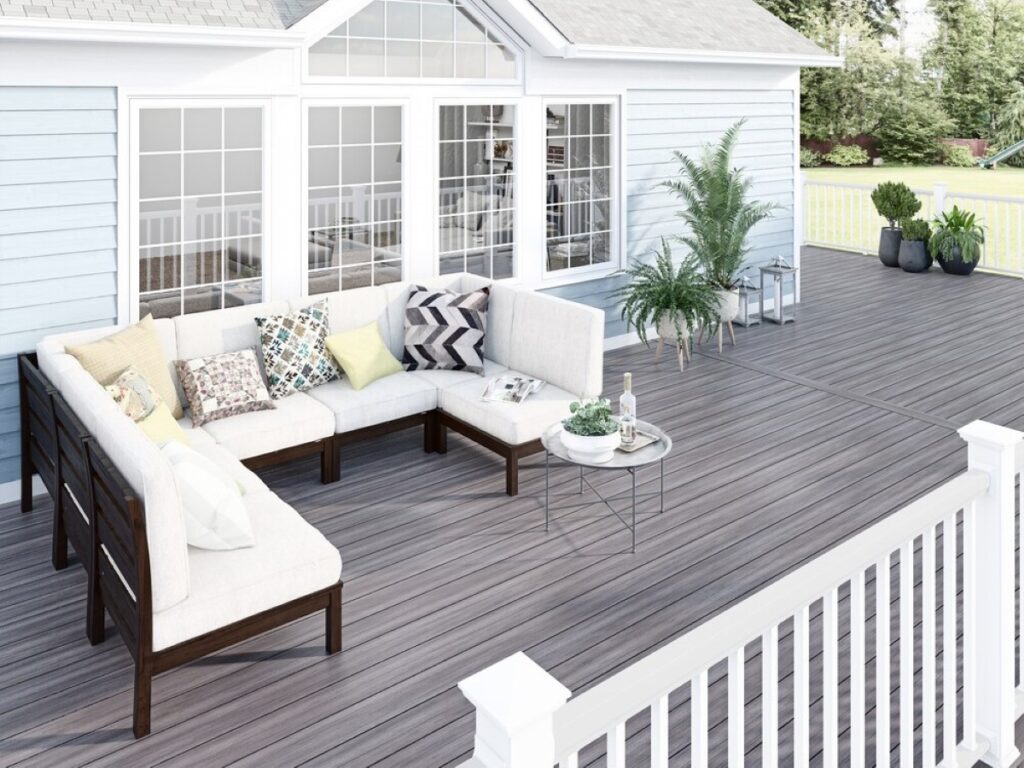 Deckorators Pioneer Lakeview Grey decking installed on a backyard deck with white railing and outdoor seating, showcasing a weathered grey tone and clean board layout.