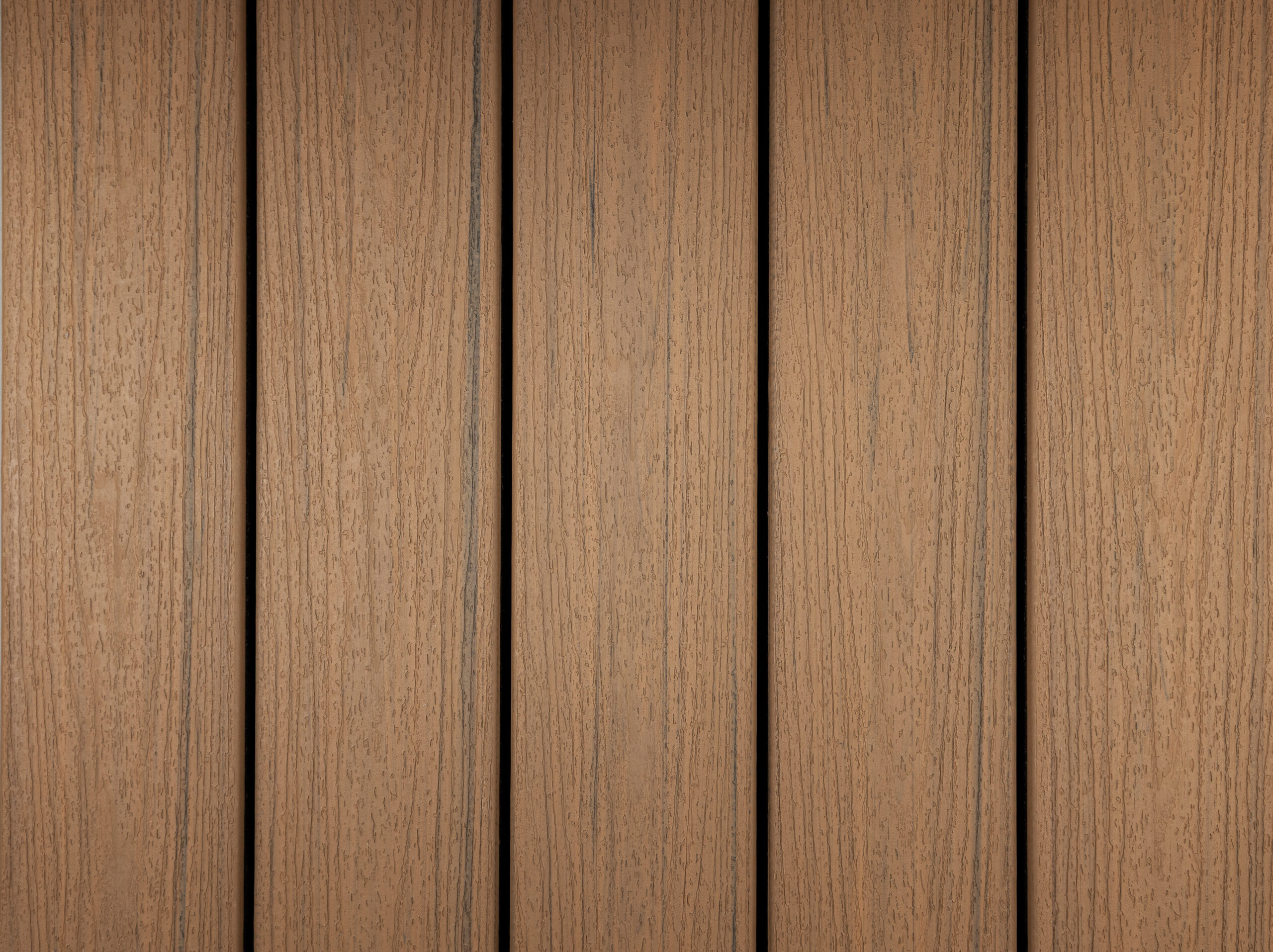 Close-up of Trex composite decking boards in the Golden Hour color showing natural wood grain texture. This warm brown composite decking color provides durability while maintaining a realistic wood appearance.