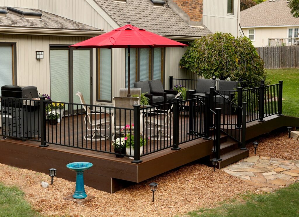 Envision Modern steel deck railing with thin vertical metal balusters and wood-toned top rail, providing a strong, modern railing system with clean sight lines.