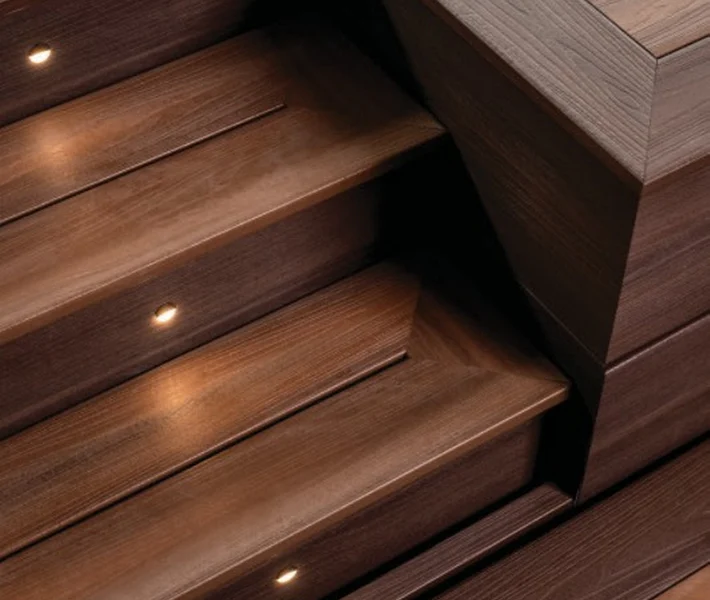 Curved composite deck stairs with integrated lighting and white railing, creating a safe and inviting outdoor space for homes in the Chicago suburbs.