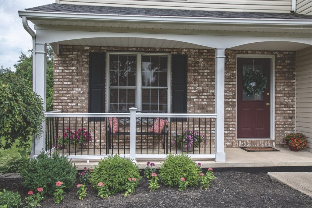 MoistureShield Discovery composite deck railing with white posts and black balusters installed on a front porch, offering a traditional style with durable, low-maintenance performance.