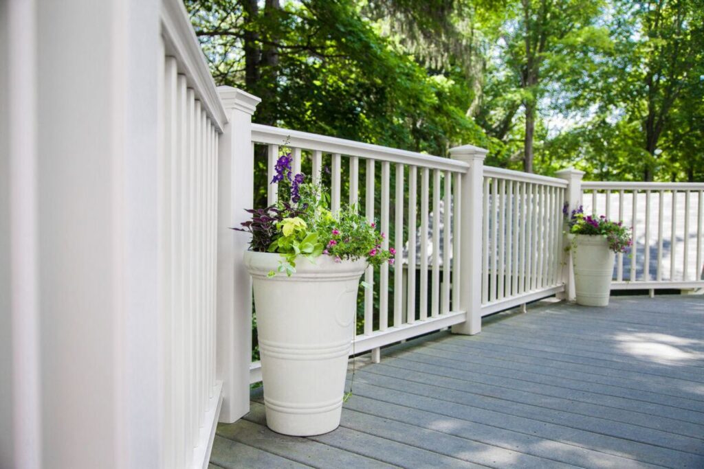 MoistureShield Navigator composite deck railing in white installed on a backyard deck with decorative planters, providing a classic look with moisture-resistant, low-maintenance materials.