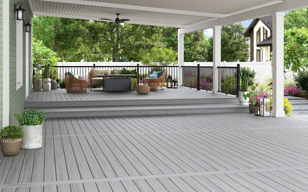 MoistureShield Stratos Santorini decking installed on a covered backyard deck with cool gray composite enhanced PVC boards, black railing, and modern outdoor seating area.