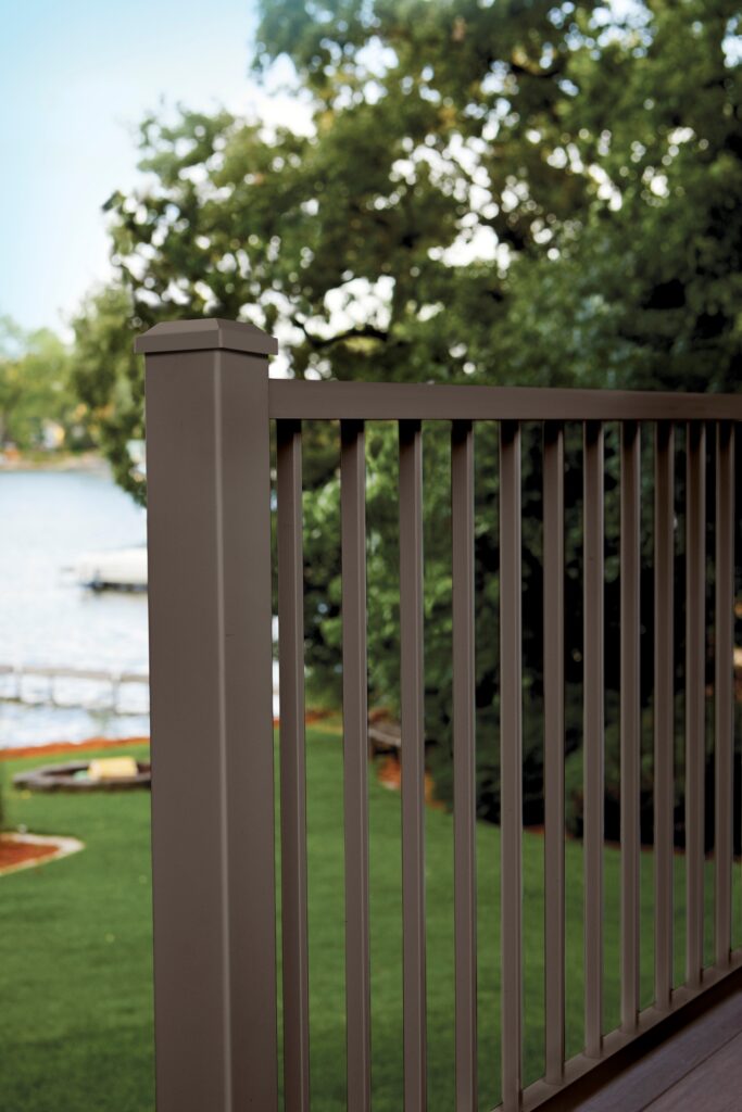 TimberTech Impression Rail Express Modern metal deck railing close-up with bronze post, bronze rails, and bronze vertical balusters.