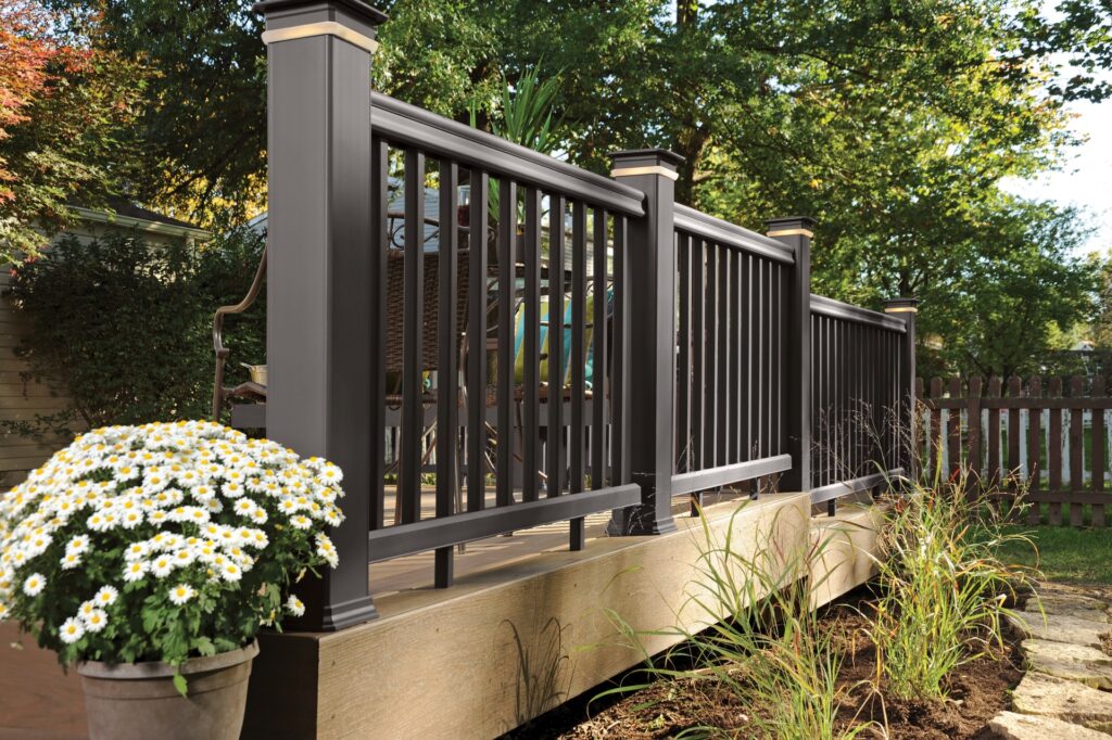 TimberTech RadianceRail composite deck railing with dark bronze posts, dark bronze rails, and dark bronze balusters beside landscaped deck.