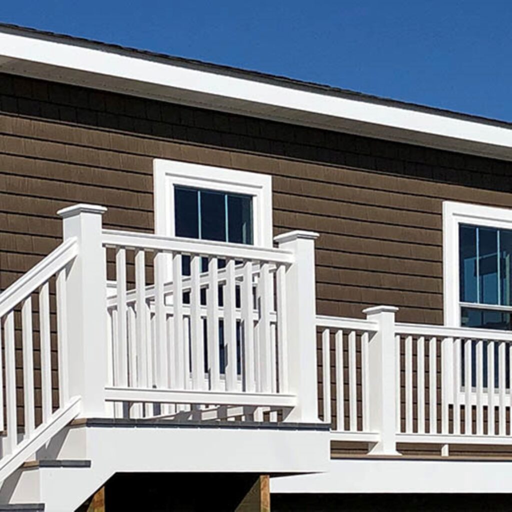 TimberTech Statement Rail PVC deck railing with white posts, white rails, and white balusters on raised deck and stair section.