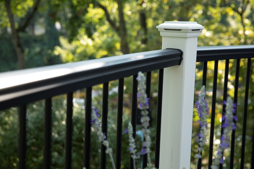 Trex Transcend composite deck railing with white posts and black balusters on backyard deck.