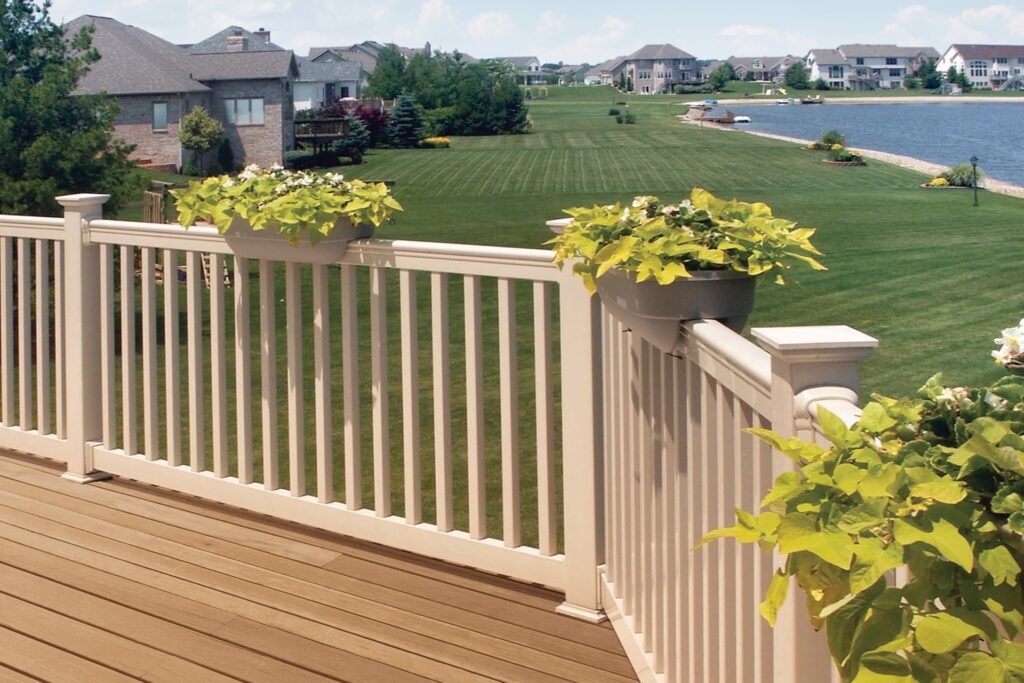Westbury Falcon vinyl deck railing in a light finish with integrated post caps and planter boxes, installed on a backyard deck overlooking a lakeside neighborhood.