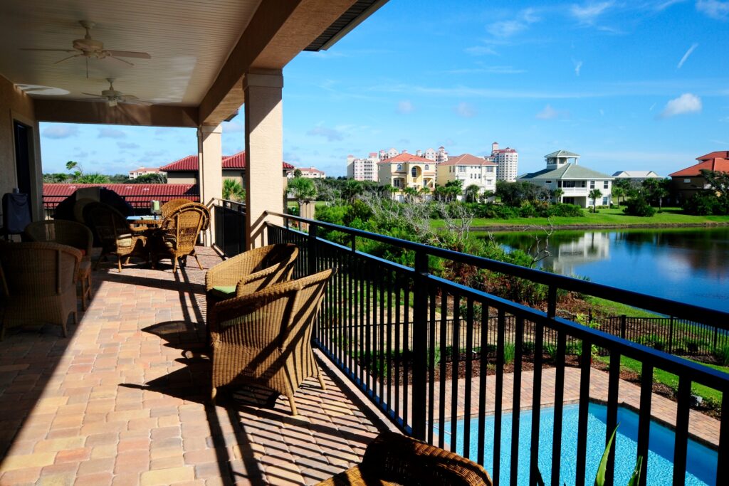 Westbury Riviera aluminum railing in black installed on an elevated balcony overlooking a waterfront community with pool and residential buildings.