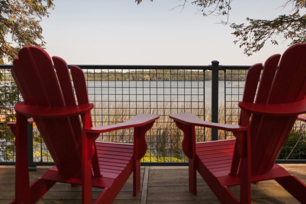 Westbury Sorrento mesh railing system with black aluminum frame and wire grid infill installed on a lakeside deck with outdoor chairs and open water views.