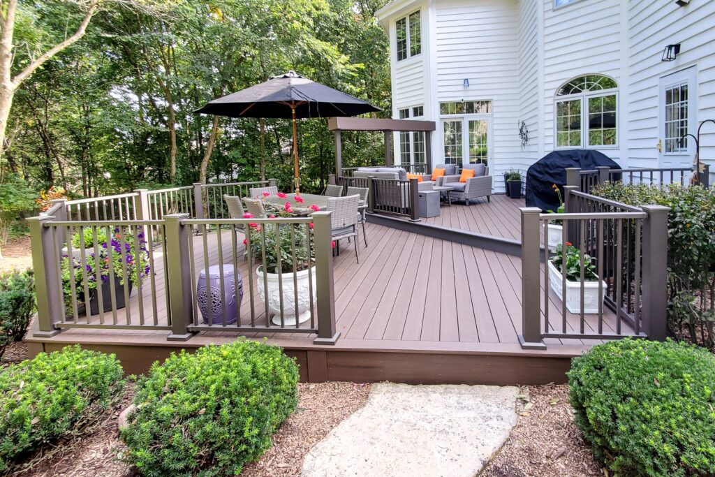 Westbury Tuscany aluminum railing in bronze installed on a multi-level backyard deck with seating area, combining classic style with low-maintenance durability.