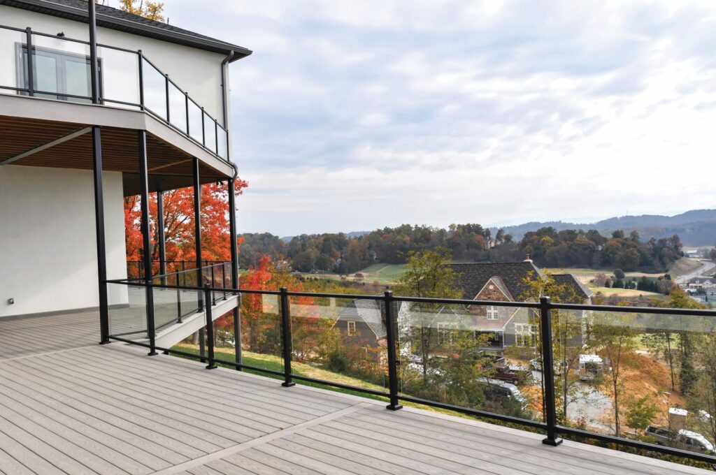 Westbury Veranda glass railing with clear panels and black posts installed on a modern elevated deck, preserving unobstructed hillside and neighborhood views.