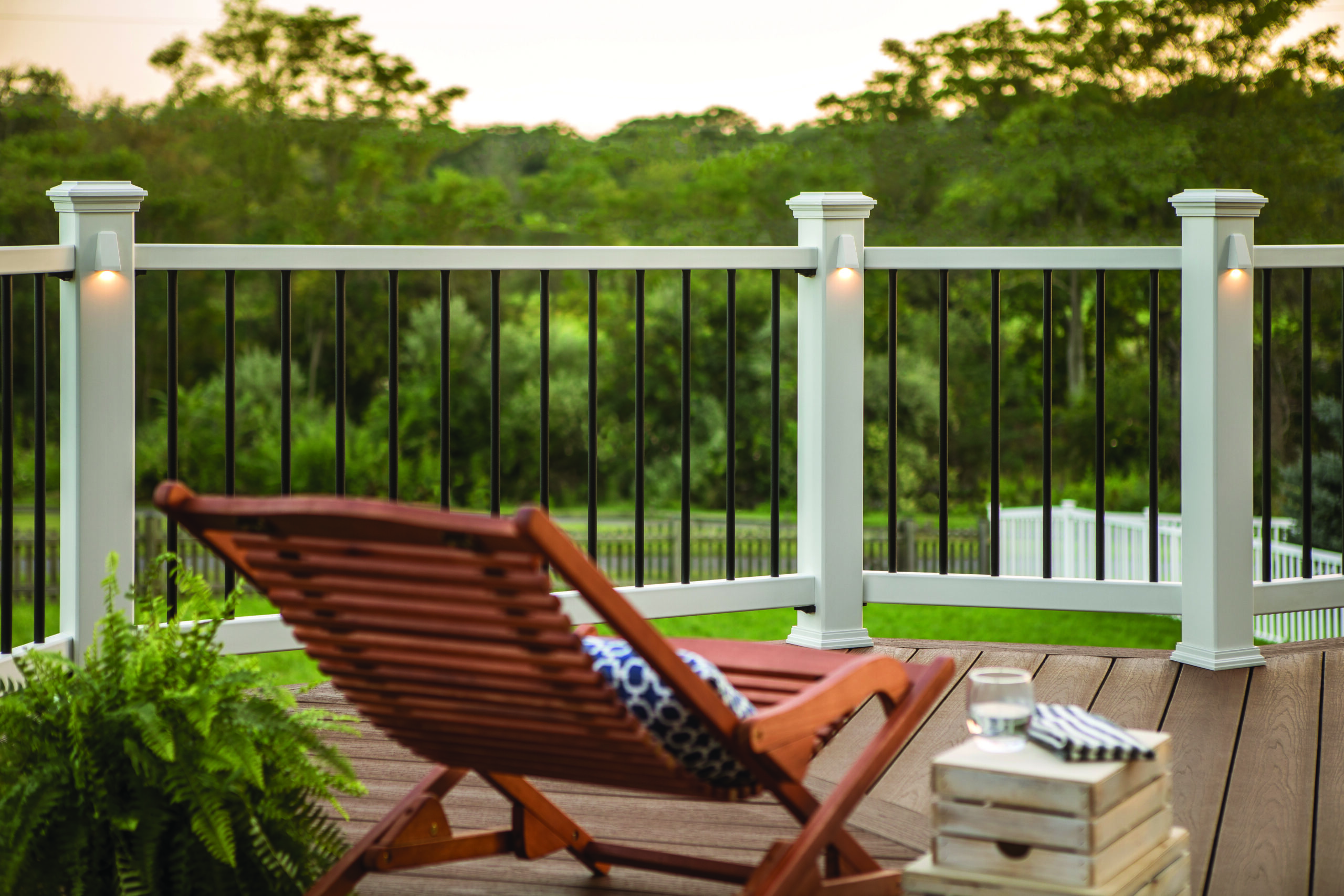 Composite deck with black metal railings and outdoor seating overlooking a green backyard, showing a typical deck vs. porch difference with its open-air design