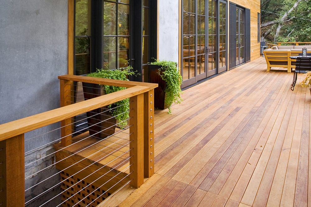 Cedar wood decking boards with cable railing on a modern outdoor deck attached to a contemporary home