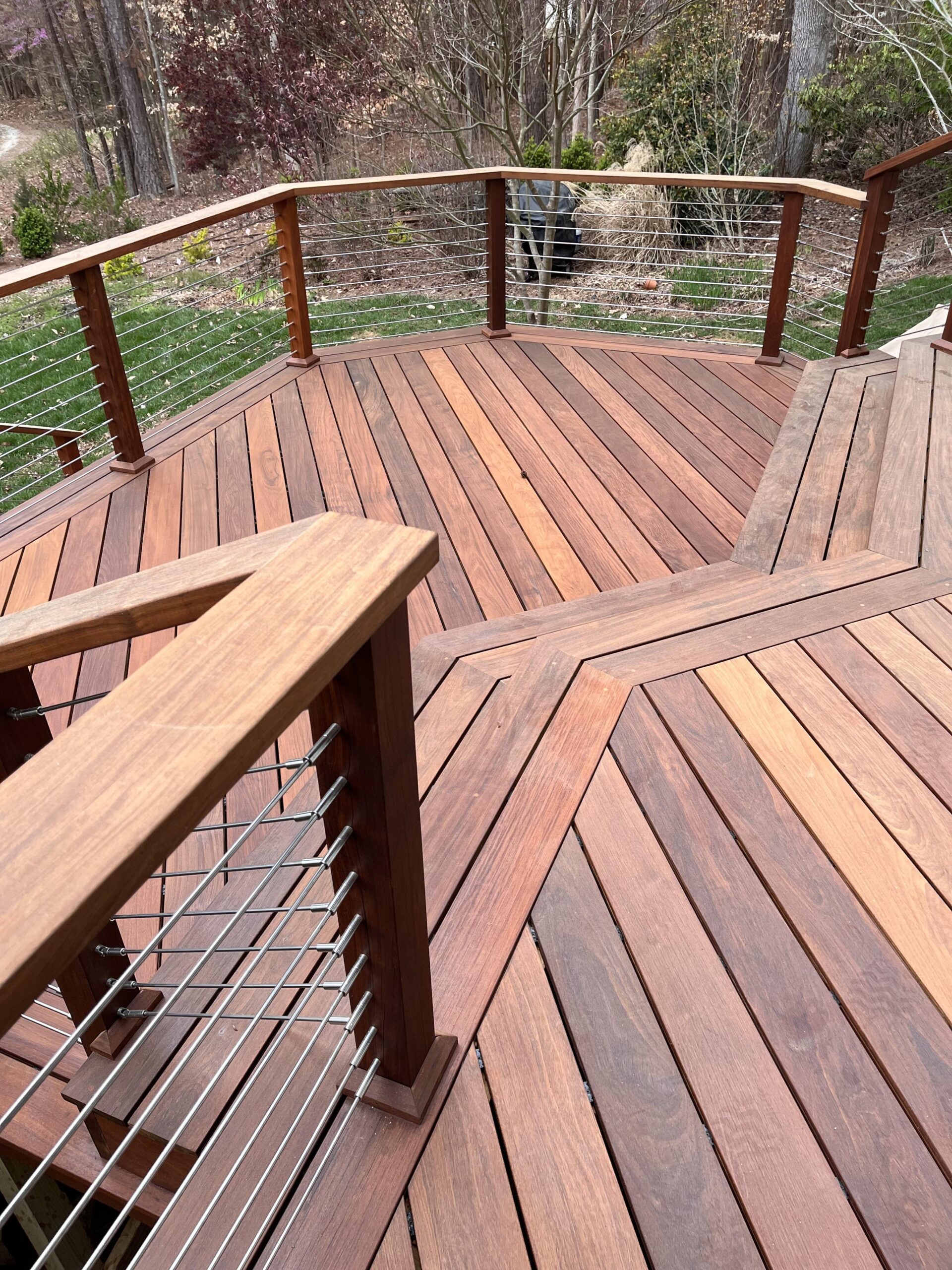 Curved ipe wood decking with cable railing showing the tight grain pattern and rich dark brown color of Brazilian hardwood