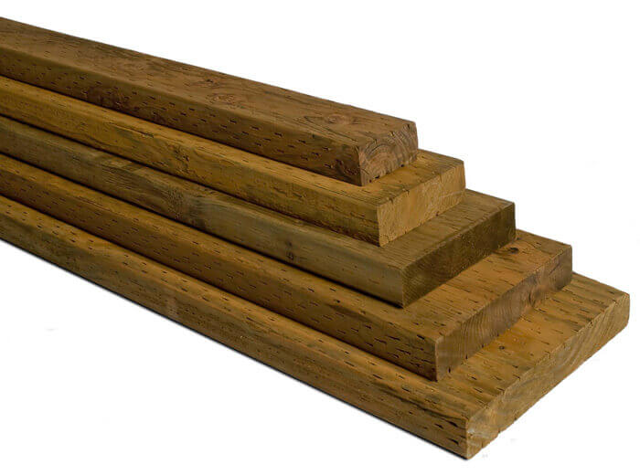 stacked pressure treated lumber boards ready to be used for an outside deck project