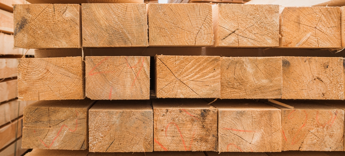 Stacked pressure treated lumber boards in various sizes showing the characteristic brown treated wood finish