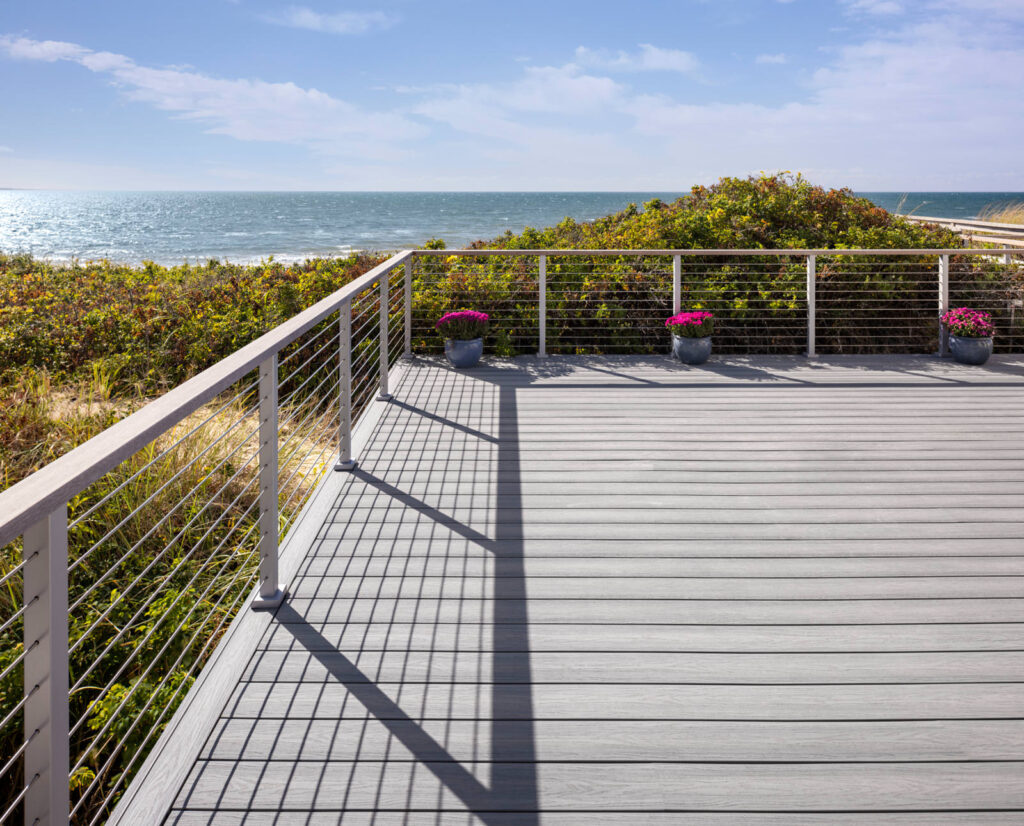 MoistureShield Elevate Alpine Gray composite deck overlooking ocean with cable railing and potted flowers