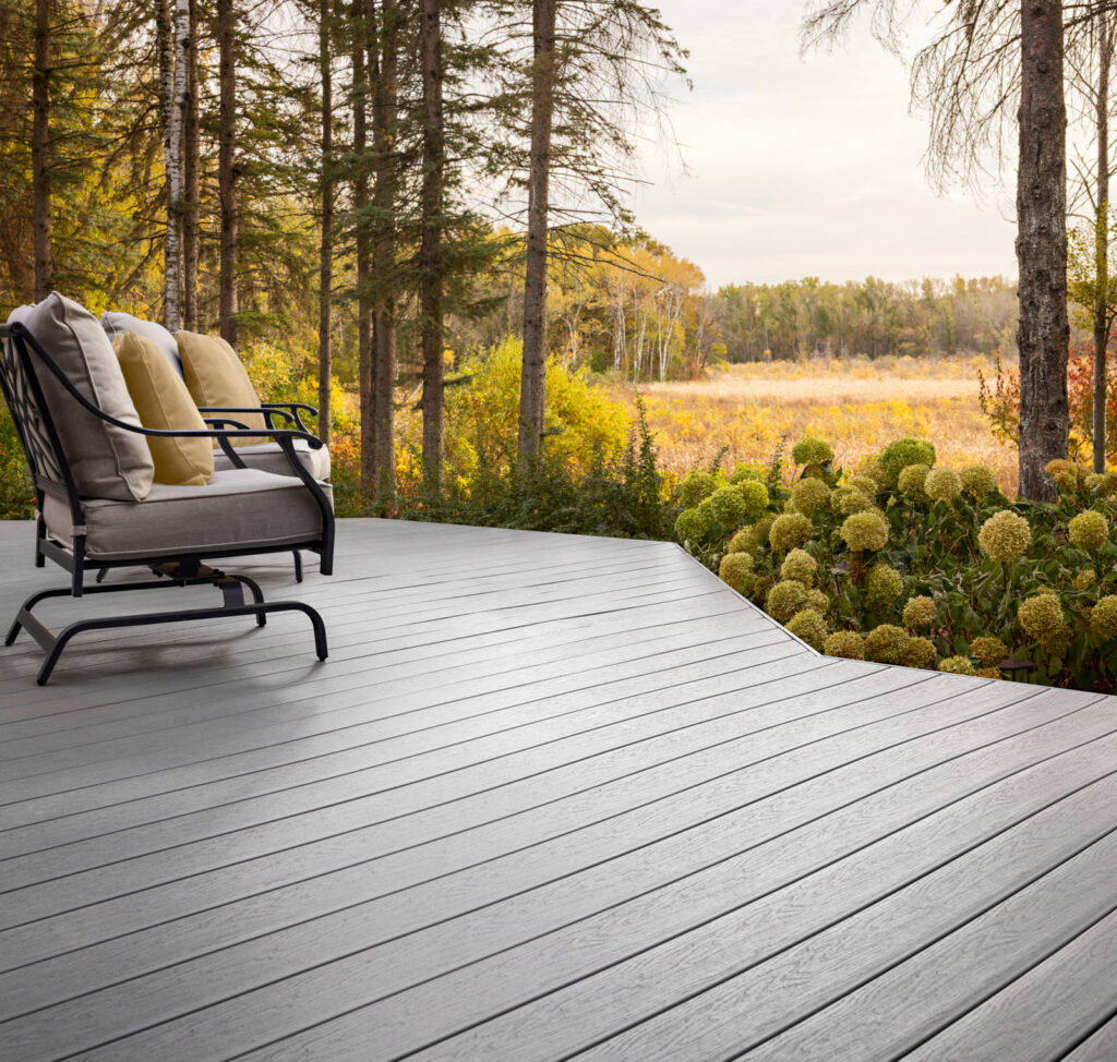 MoistureShield Elevate Lake Fog composite deck curved edge with chair overlooking meadow and trees