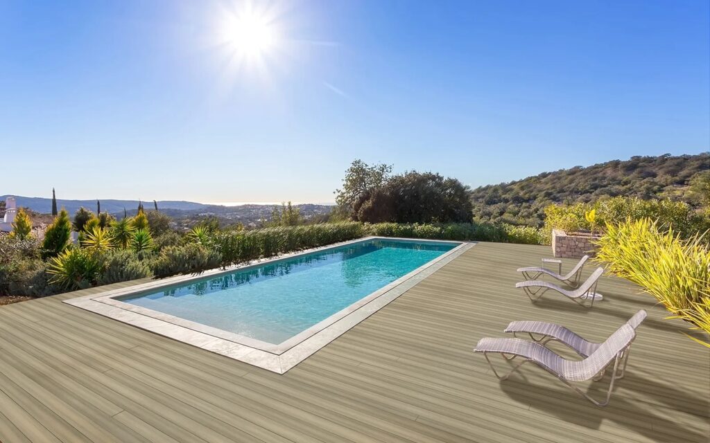 MoistureShield Meridian Shoal composite deck surrounding pool with lounge chairs and hillside view