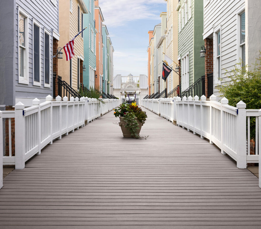 MoistureShield Vantage Cape Cod Gray uncapped composite boardwalk with white railings between coastal homes