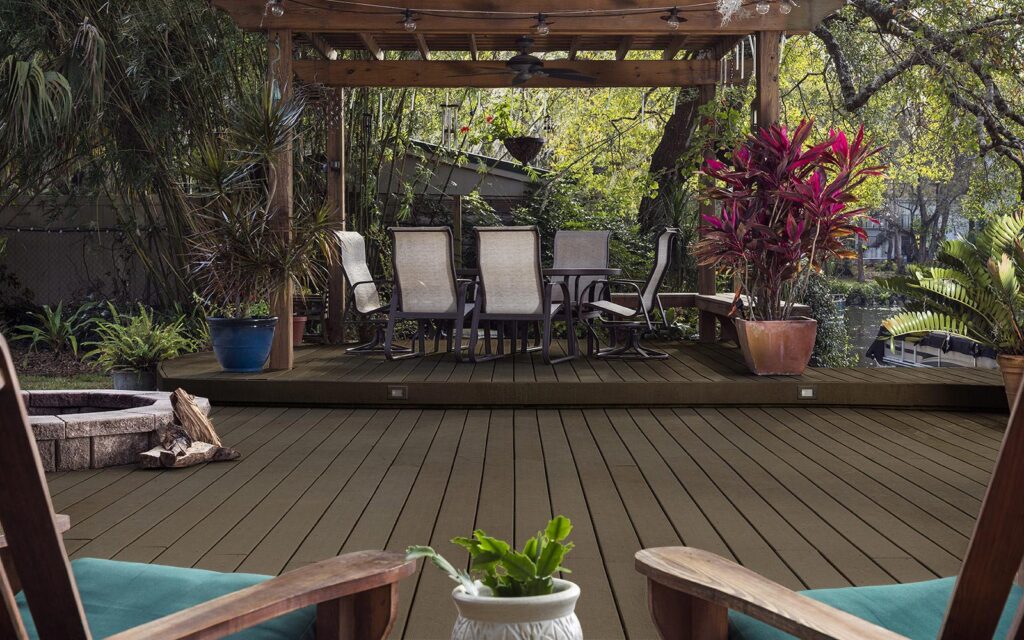 MoistureShield Vantage Earthtone uncapped composite deck under pergola with fire pit and pond view
