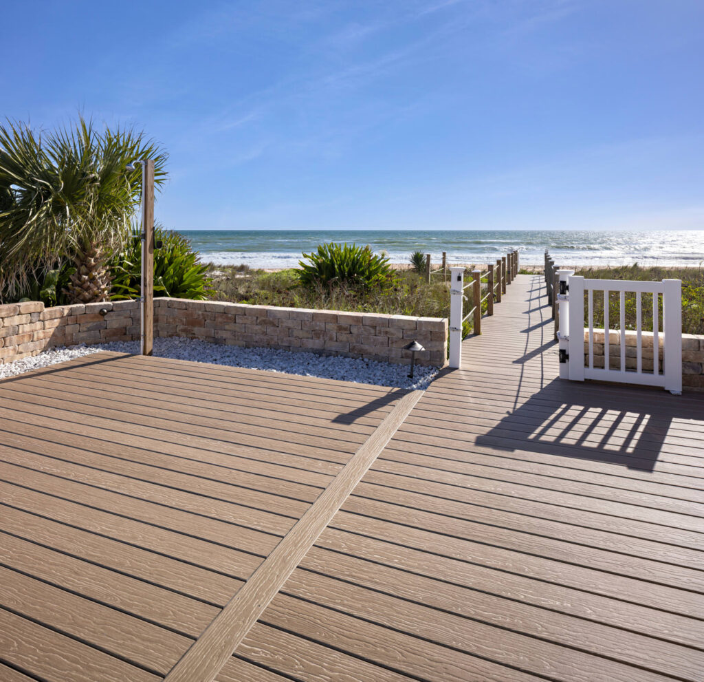 MoistureShield Vision Mochaccino composite deck boardwalk leading to beach with gate and stone wall