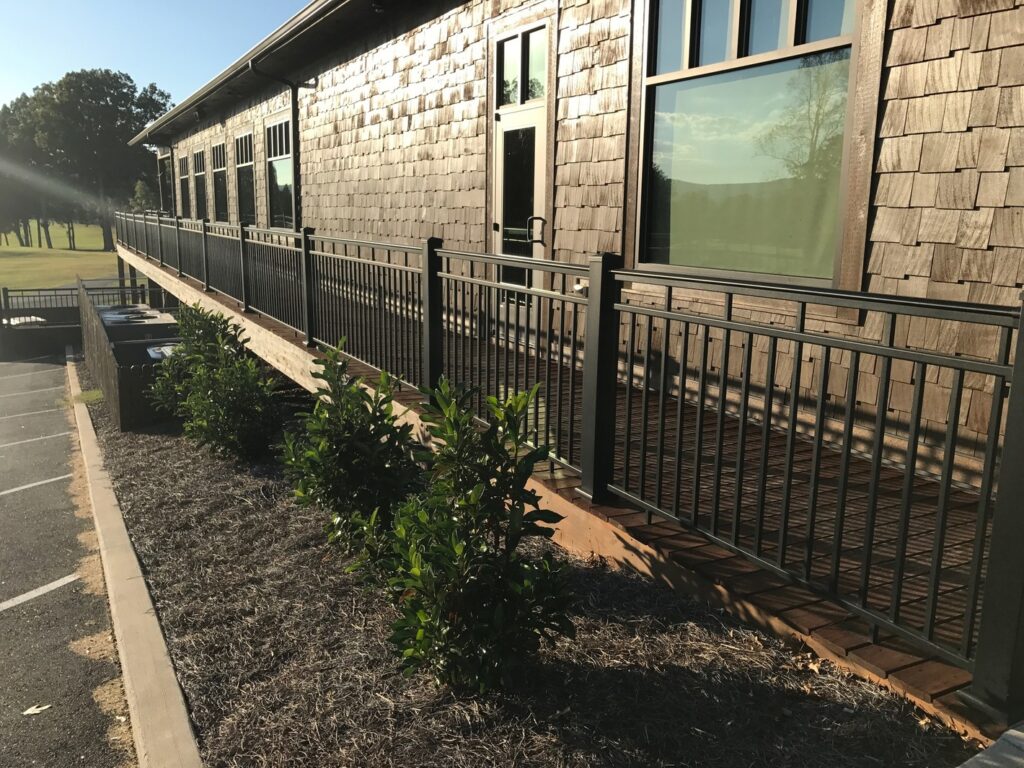 AFCO Series 125 aluminum railing running along a commercial access ramp beside a cedar shake building, metal deck railing ideas for sloped runs
