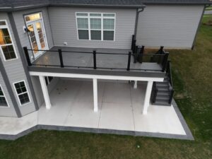 Elevated gray composite deck with black glass railing above a concrete patio in St. Charles, IL