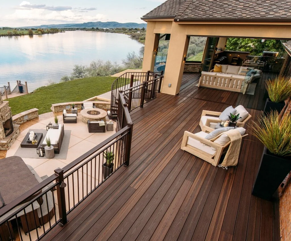 Envision composite decking in a dark espresso tone on a lakefront deck with a fire pit and black railing