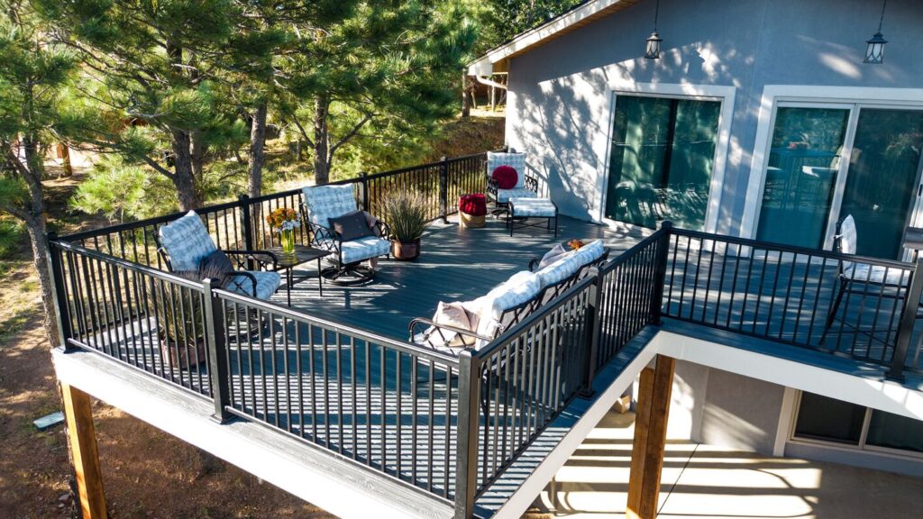 Black Envision Fairway Designer aluminum railing wrapping an elevated gray composite deck among pines.