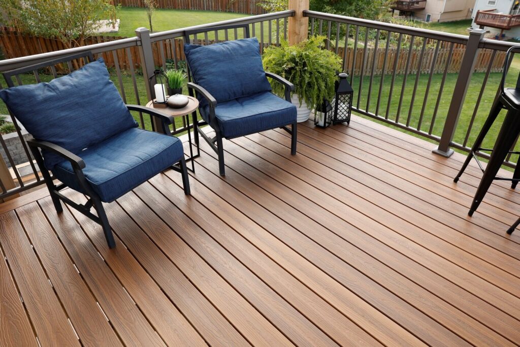 Bronze Envision Fairway Designer aluminum railing on a warm brown composite deck with blue cushions.