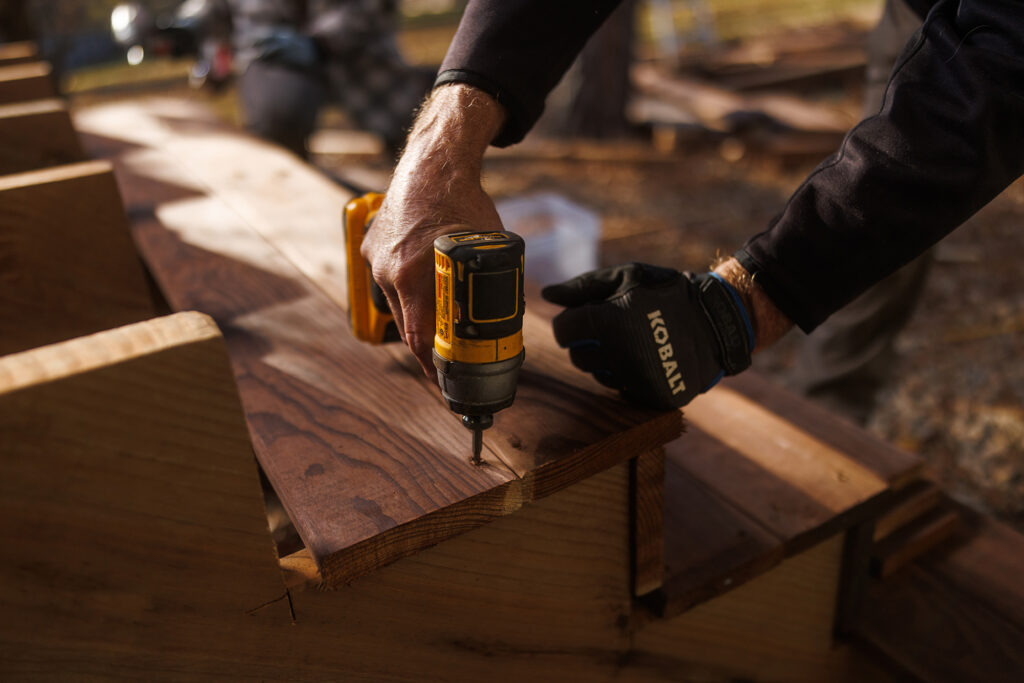 Installer driving a screw through a stair tread into a ProWood treated stringer with an impact driver.