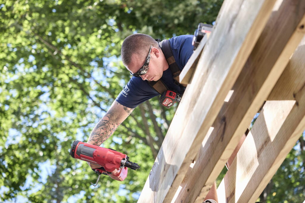 Carpenter fastening ProWood treated deck joists with a framing nailer during deck substructure installation.