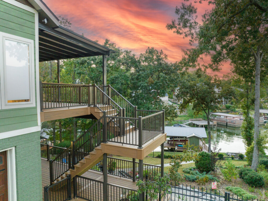 KeyLink American Series aluminum railing on a multi-level lakefront deck with switchback stairs at sunset.