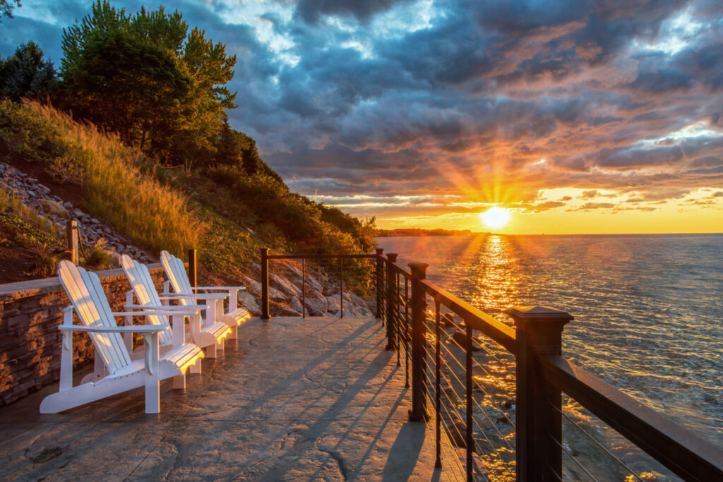 Black KeyLink American Series horizontal cable railing along a stone patio overlooking a lake at sunset.