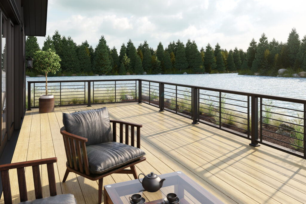 Bronze KeyLink Chesapeake railing with horizontal rod infill on a blonde composite deck facing a pine-lined lake.