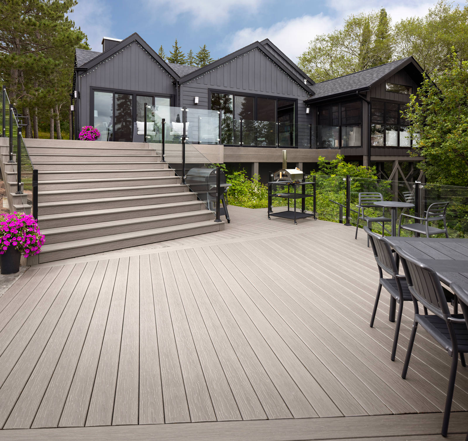 MoistureShield composite decking in weathered gray on a wide lakeside deck with glass railing and stairs