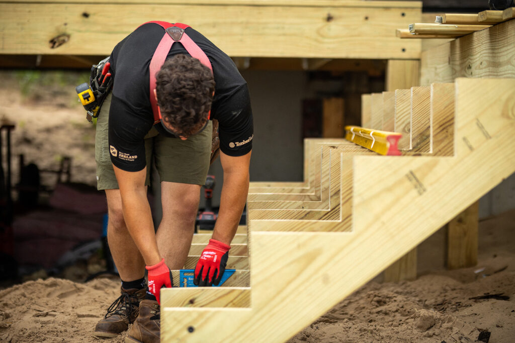 Carpenter checking notch layout with a speed square on cut ProWood treated 2x12 stair stringers.