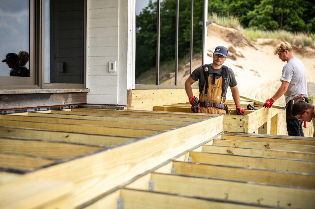 Crew framing a lakeside deck with ProWood treated joists set 16 inches on center over a taped ledger.