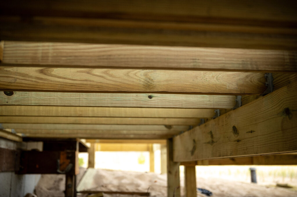 ProWood treated deck joists and beam underside showing ground contact substructure on galvanized hangers.