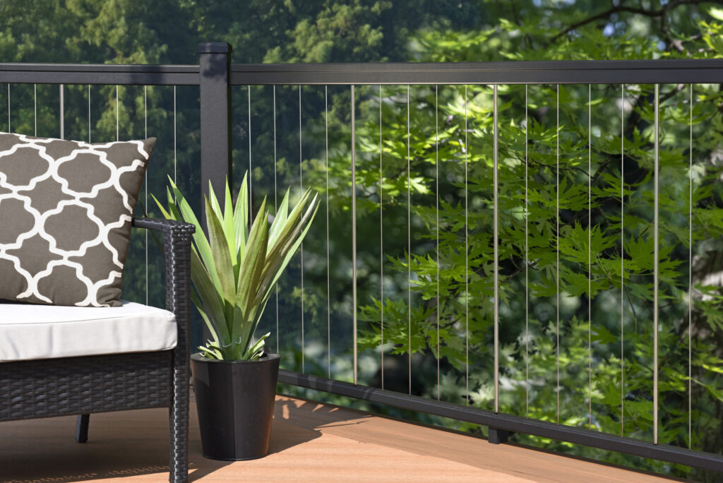 Black TimberTech Impression Rail Express with vertical stainless cable infill against a wooded backdrop, modern metal deck railing ideas