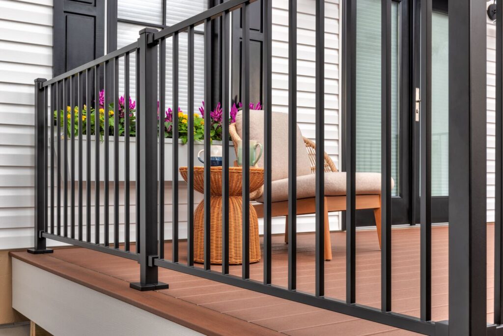 Black Trex Enhance Steel railing with square balusters on a sand-colored composite deck and stair run.